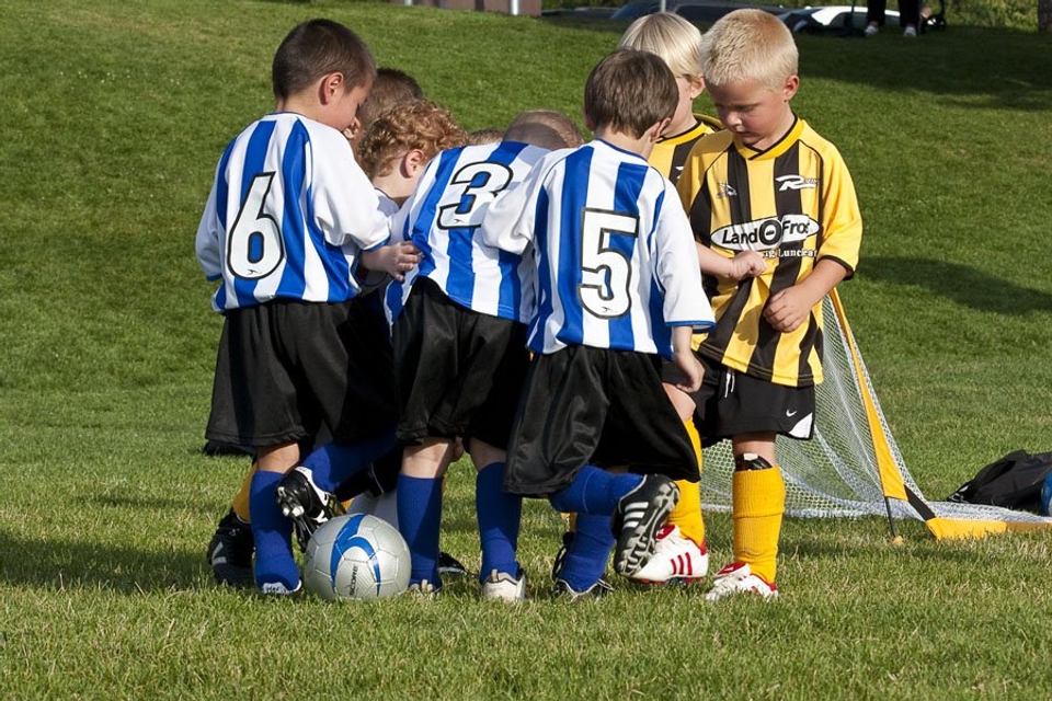 A group of children playing soccer on a grassy field