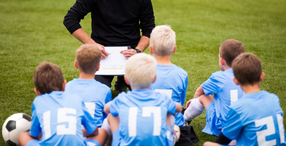 Grassroots football players being shown tactics board