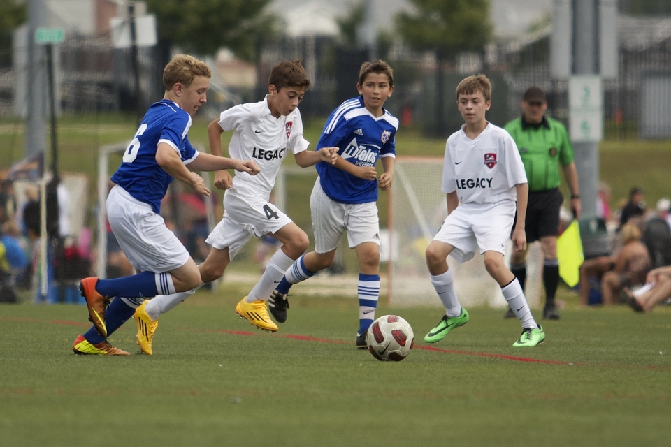 kids battle for ball in football match