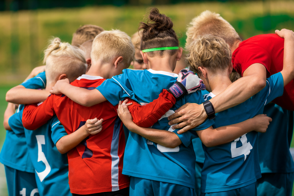 A group of children in a huddle before a Grassroots football match